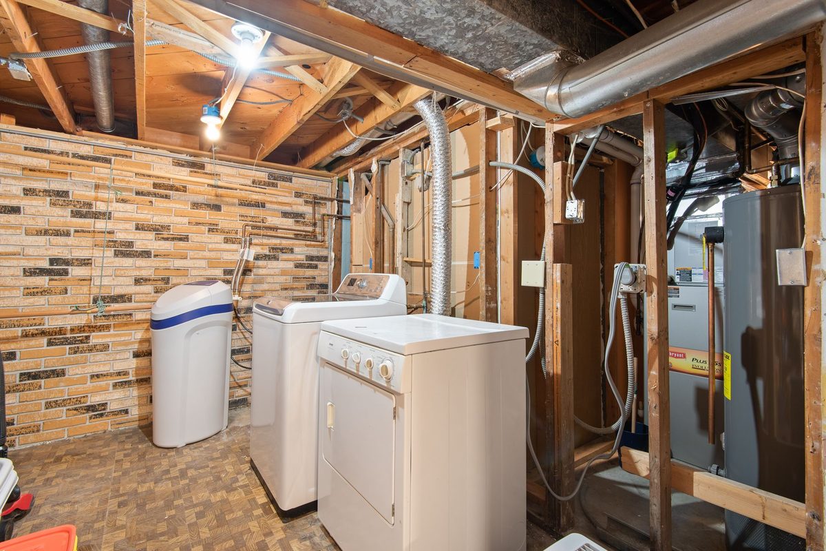 Unfinished basement utility room with pipework along the wall